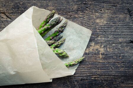 Bunch of fresh organic green asparagus from farm market on an old wooden background with place for text. Healthy food concept. Top view. Copy space.の写真素材