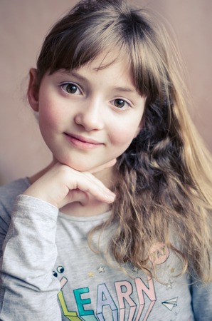 Portrait of little pretty girl with cute smile. Beautiful girl with long dark blonde hair and...