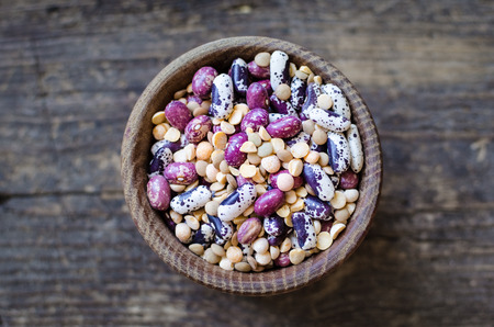 Assortment of dry organic beans and lentils in bowl on rustic wooden table. Variety of raw legumes....