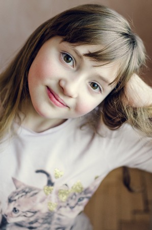 Portrait of little pretty girl with cute smile. Beautiful girl with long dark blonde hair and wonderful expressive brown eyes. Little lady schoolgirl 8 years old. Close up.の写真素材