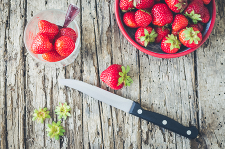 Ripe strawberries on a cutting board with a knife.の写真素材