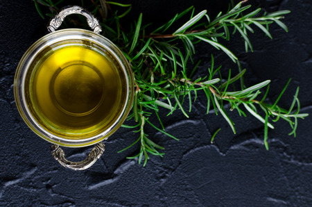 Rosemary and olive oil on dark stone table. Herbs and spices concept. Cooking ingredients. Food flat lay. Top view.の写真素材