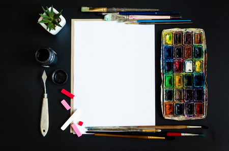 Creative artist workplace flat lay, mockup. Top view on table with blank sheet of paper, paintbrushes and dye palettes. Art, workshop, painting, drawing, craft, creativity concept. Copy space.の写真素材