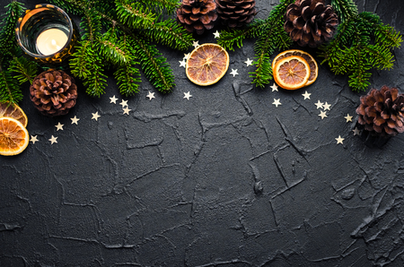 Christmas fir tree branches with dried orange slices, pine cones and stars on black background with space for text. Merry Christmas and Happy New Year. Xmas concept. Top view. Copy space.の写真素材