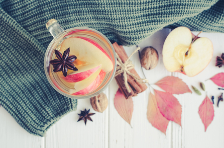 Autumn mulled wine or gluhwein based on white wine with rum, apple and spices cinnamon sticks, star anise, nutmeg, cardamom and clove on white wooden background. Seasonal beverages recipe. Top view.の写真素材