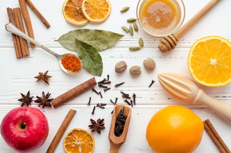 Christmas spices and ingredients for mulled wine or gluhwein with orange, cinnamon sticks and anise on white wooden background. Spicy warm beverage. Seasonal mulled drink. Top view.の写真素材