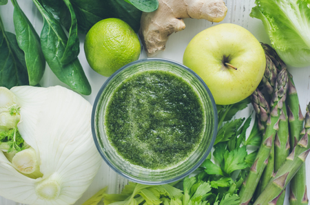 Green fruit and vegetable smoothie with ingredients: spinach, lettuce, fennel, celery, ginger, lime, apple and asparagus on white wooden background. Spring detox concept. Healthy eating. Top view.の写真素材