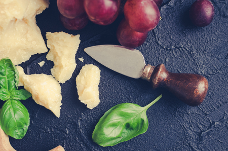 Italian style food set - Parmesan cheese, grapes and basil. Mediterranean appetizers, tapas or antipasti on black background. Delicious snack on party. Top view.の写真素材