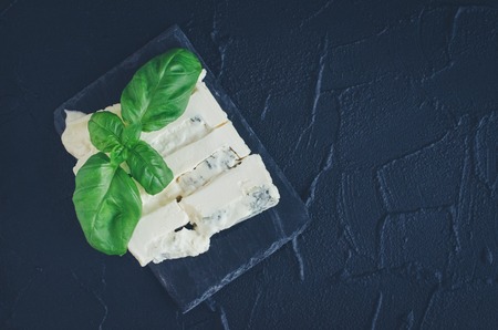 Gorgonzola cheese with mascarpone with basil on slate plate on dark background with place for text....