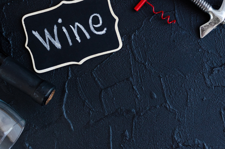 Bottle of wine with two vintage corkscrews on black stone background. Traditional winemaking and wine tasting concept. Top view. Copy space.の写真素材