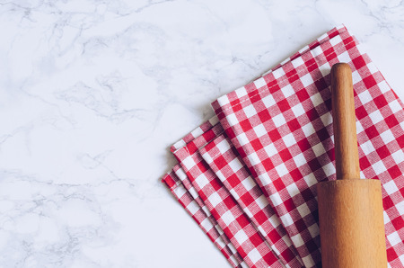 Wooden rolling pin on red checkered napkin on marble  with place for text.の写真素材