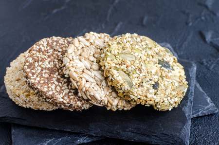 Healthy dessert cereal snacks. Fitness dietary super food. Kozinaki with sesame,flax, peanuts, sunflower and pumpkin seeds at the shale plate. Vegetarian-vegan healthy nutrition concept. Copy space.の写真素材