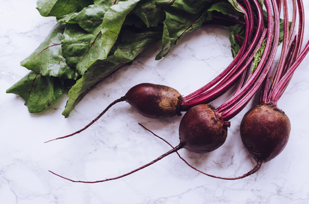 Bunch of homegrown organic young beets with green leaves on the table. Fresh harvested beetroots on...