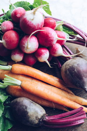 Raw organic vegetables carrot, radish and beetroot on the table. Healthy clean eating. Different colorful vegetables on wooden board.の写真素材