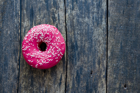 Donuts with pink icing on wooden background with place for text. Creative layout made of pink donuts. Flat lay. Food concept. Minimal style. Top view. Copy space.の写真素材