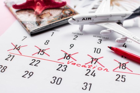 Vacation planning concept. Travel preparation: passport and vacation plan written on calendar on pink background.の写真素材