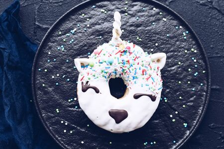 Unicorn donut over dark background. Trendy doughnut unicorn with white glaze. Top view or flat lay.の写真素材