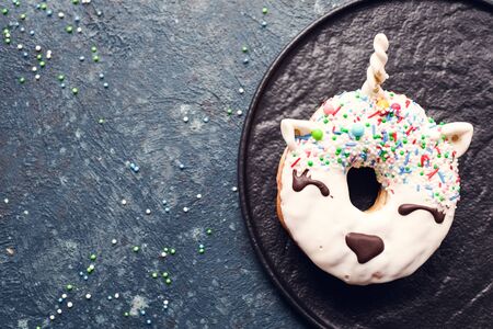 Unicorn donut over dark background. Trendy doughnut unicorn with white glaze. Top view or flat lay. Copy space.の写真素材