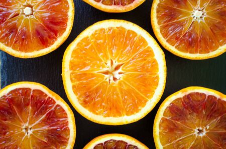 Sliced blood oranges texture. Citrus background. Cut ripe juicy Sicilian Blood oranges fruits on back background. Top view.の写真素材