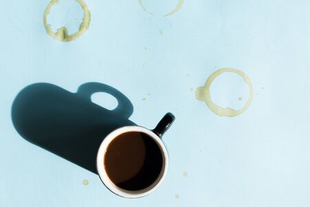 Coffee mug with stains and splashes over blue background. Top view.