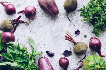 Flat-lay of green and purple raw vegetables over grey background, food frame. Local produce for healthy cooking.の写真素材