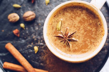 Coffee with spices over black plate. Beverage with caffeine and spices. Seasoning. Cinnamon. Badian. Coffee house. Top view.の写真素材
