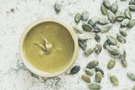 Seeds butter in glass jars with ingredients. Homemade raw organic pumpkin seeds paste on a table. Top view.の写真素材