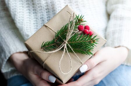 Womans hands hold Christmas or New Year decorated gift box.