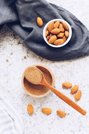 Almond nut butter in glass jar. Homemade raw organic almond nuts paste on grey background. Healthy natural food concept. Top view.の写真素材