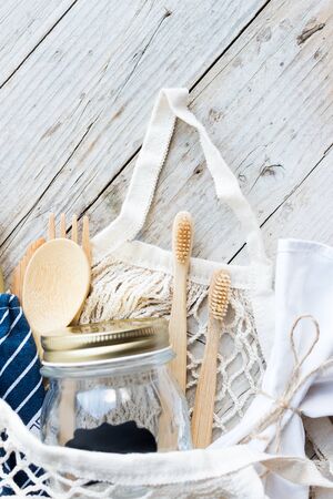 Zero waste concept. Cotton bags, glass jar, bamboo cutlery and toothbrushes on wooden background. Sustainable living. Eco friendly plastic free items. Top view.の写真素材