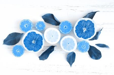 Assorted fresh citrus fruits with leaves on white wooden table.の写真素材