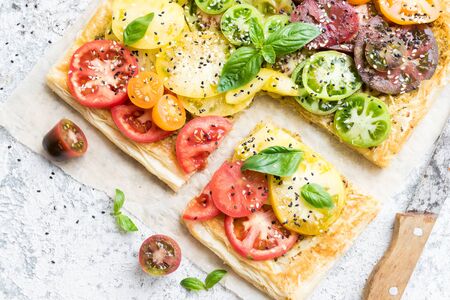 Vegetable puff pastry tart with fresh colorful tomatoes and basil.の写真素材