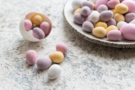 Easter composition with mini chocolate eggs in pastel colors on grey concrete