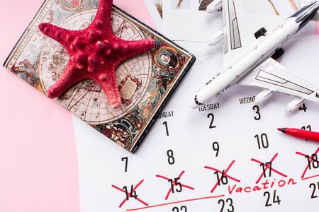 Vacation planning concept. Travel preparation: passport and vacation plan written on calendar on pinkの写真素材