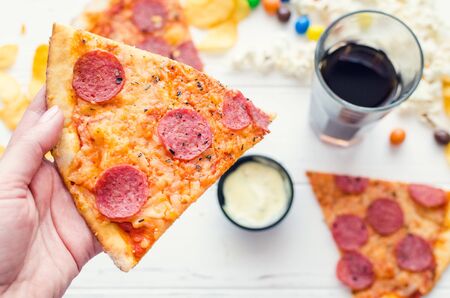 Fast food and unhealthy eating concept. Close up of fastfood snacks: pizza, popcorn, potato chips...