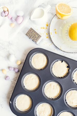 Process of preparation glazed Easter cupcakes decorated with mini chocolate eggs candy on white...
