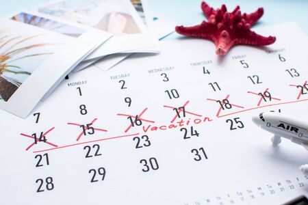 Travel preparation: camera, passport and vacation plan written on calendar on blueの写真素材