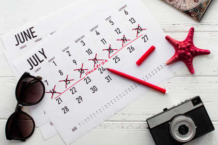 Vacation planning concept. Travel preparation: camera, passport, vacation plan written on calendar...