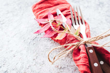 Thanksgiving autumn place setting with cutlery and arrangement of fall leaves on grey background. Thanksgiving holidays background concept. Copy space.の写真素材