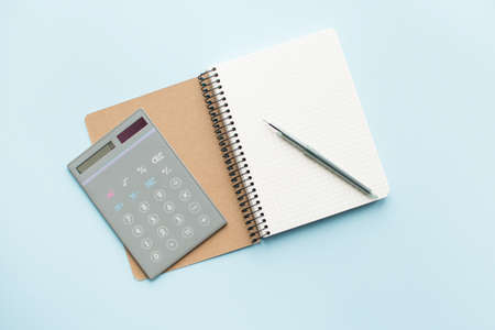 Paper notebook with calculator and pen on blue background. Healthy eating concept - calculate daily nutrition intake. Top view.の写真素材