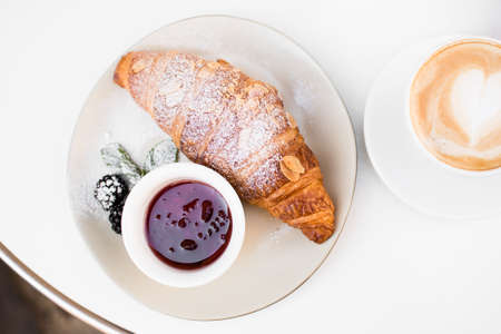 Cup of coffee with heart drawing, croissant and jam on black background. Breakfast on Mothers day, Valentines Day or Women's day. Romantic morning concept. Top view.の写真素材