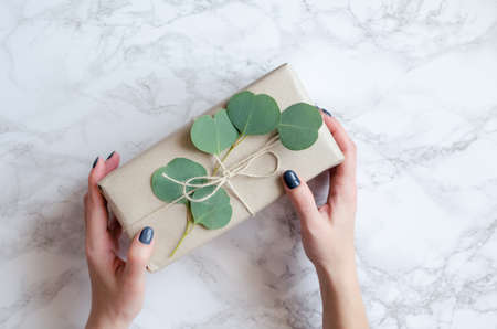 Gift box wrapped in brown paper decorated with eucalyptus branch, natural eco friendly zero waste gift wrapping idea. Top view.の写真素材