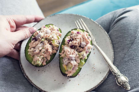 Woman hold plate with salad of avocado, red onion, celery and tuna on white background. Healthy food concept. Top view.の写真素材