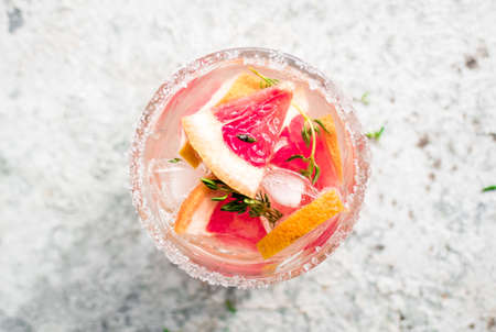 Glasses of Grapefruit drink with ice cubes and thyme. Summer refreshing cocktails. Top view.