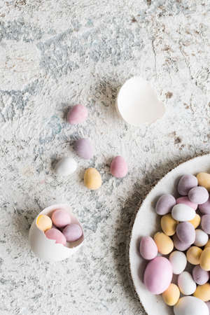 Easter composition with mini chocolate eggs in pastel colors on grey concrete background. Happy Easter Holidays. Top view. Copy space.の写真素材