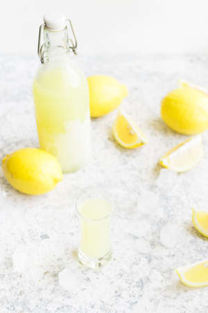 Traditional homemade lemon liqueur limoncello and fresh citrus on the table. Italian traditional liqueur limoncello with lemon. Italian alcoholic beverage.の写真素材