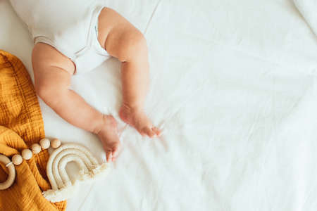 Baby playing with a wooden toy on white linens background. Mockup. Top view. Copy space.の写真素材