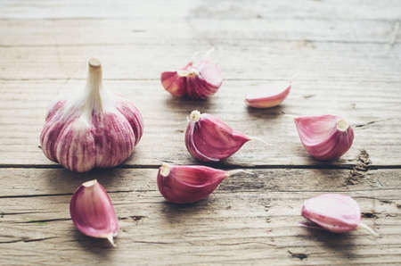 Rustic style garlic on vintage wooden background. Fresh young peeled purple garlic.