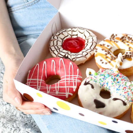 Woman holding box of delicious donuts. Party concept. No diet. Candy bar. Proper nutrition or sweets, dessert fast food, dieting morning concept.の写真素材