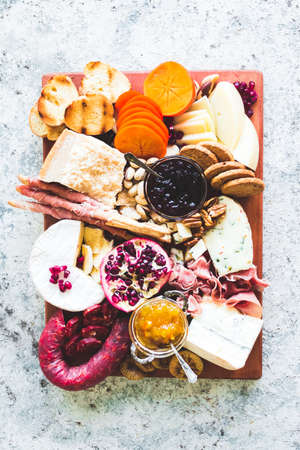 Charcuterie board. Cheese platter: Parmesan, caciocavallo, camembert and other with prosciutto, salami, fruits and nuts. Assortment of tasty appetizers or antipasti. Top view.の写真素材
